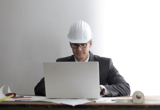 man in hardhat using laptop