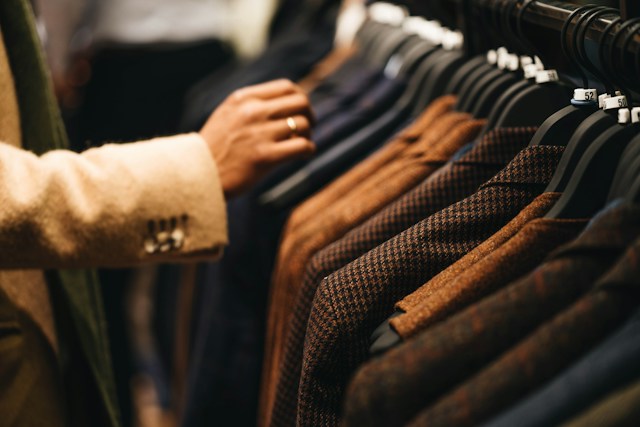 men's suits on the rack with hand reaching in