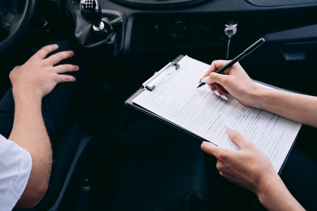person writing on clipboard inside car