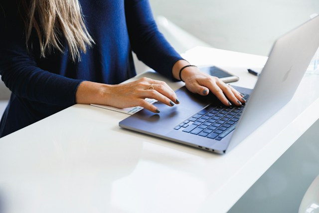 close-up of woman's hands typing on laptop