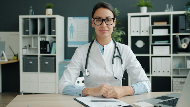 pretty femal doctor sitting at her desk wearing glasses