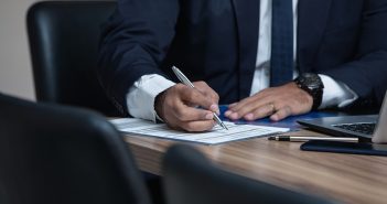 man in suit writing on table