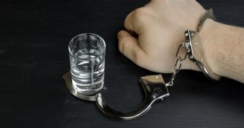 man's hand handcuffed to shot glass