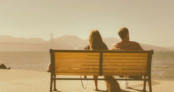 rear view of woman and man sitting on bench with vintage feel
