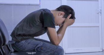 man with face in hands side view