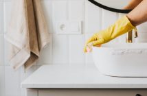 person with gloves cleaning bathroom