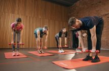 people in workout group with dumbells and matts