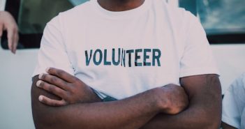 man in white shirt that spells out volunteer