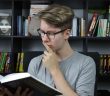 male student in glasses reading book