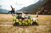 men and women jumping around a car