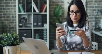 woman sitting and looking at phone and credit card