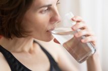 woman in black tank top drinking glass of water