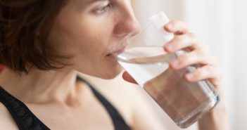 woman in black tank top drinking glass of water