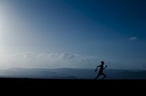 man running at dusk with landscape behind him