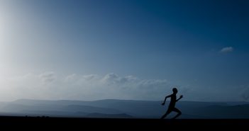 man running at dusk with landscape behind him