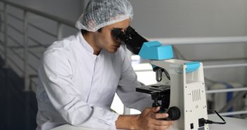 researcher in a lab looking into microscope