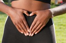 black woman in yoga pants holding her belly