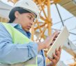 female construction worker in hardhat sing touchscreen device