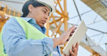 female construction worker in hardhat sing touchscreen device