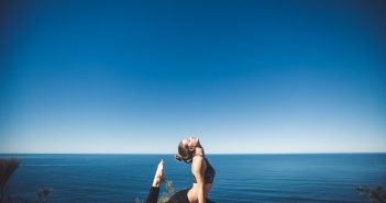woman doing yoga in black yoga pants near water