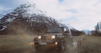 Jeep on road in cold weather near white capped mountain