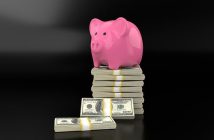 pink piggy bank sitting on stack of money