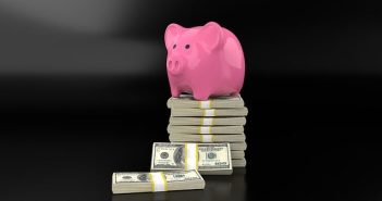 pink piggy bank sitting on stack of money