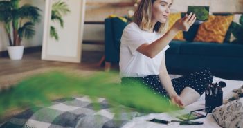 pretty woman sitting on bed applying makeup