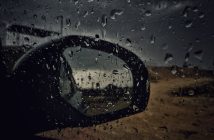 side mirror on car with water droplets seen through side car window