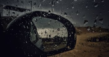 side mirror on car with water droplets seen through side car window