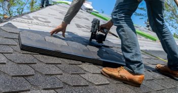 closeup of roofer standing on roof installing shingle