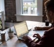 man working on laptop on table with window in background