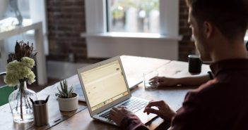 man working on laptop on table with window in background