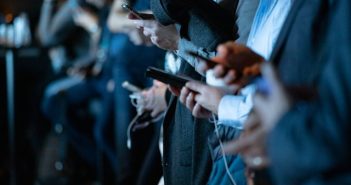 people using their phones while standing cropped view