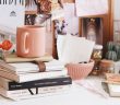 light brown ceramic coffee mug on stack of books on cluttered shelf