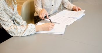 closeup of two women working on papers on table
