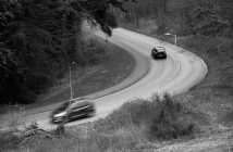 black and white photo of two cars driving on winding road