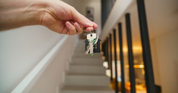 closeup of hand holding keys with stairs in background