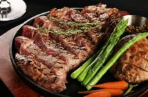 closeup of juicy steak on plate with veggies and potatoes