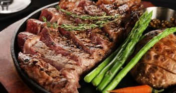 closeup of juicy steak on plate with veggies and potatoes