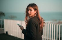 pretty woman with long brown hair holding smartphone and looking back over her shoulder