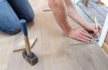 person kneeling on floor writing with pencil