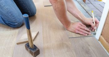 person kneeling on floor writing with pencil