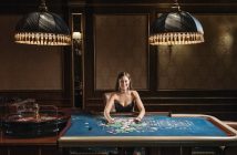 woman sitting next to gaming table in casino