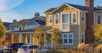 yellow house with white trim with two cars parked in front