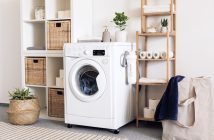 white front loading washing machine next to wooden shelves
