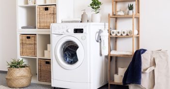white front loading washing machine next to wooden shelves