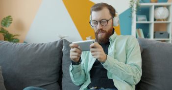 ,an with beard and headphones playing game on smartphone