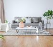 gray couch and white chair and gray rug in living room with white wall and hardwood floor