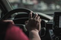 person's hand on car steering wheel